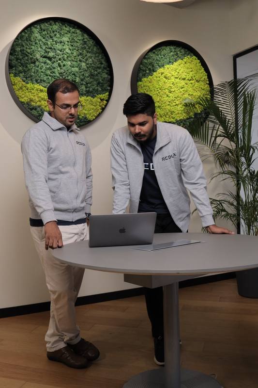 Redux team members collaborating at a laptop